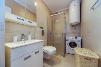 a bathroom with a toilet sink and a washing machine at Apartments Monte Re in Petrovac na Moru