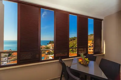 a dining room with windows with a table and chairs at Apartments Monte Re in Petrovac na Moru