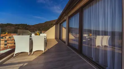 a balcony with white chairs and a view of a building at Apartments Monte Re in Petrovac na Moru