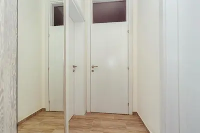 a hallway with white doors and wood floors at Apartments Monte Re in Petrovac na Moru