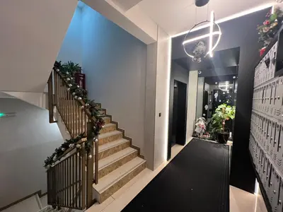 a staircase in a house with a black floor and a chandelier at Fanky City Apartments in Podgorica