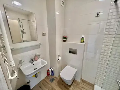 a white bathroom with a toilet and a sink at Fanky City Apartments in Podgorica
