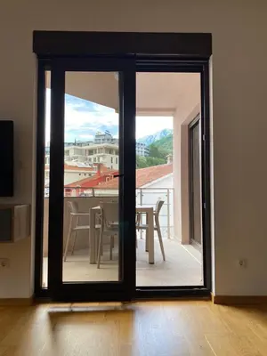 a sliding glass door with a view of a table at Apartmani Jedro in Rafailovici