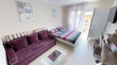 a living room with a purple couch and a bed at Adagio apartment in Cetinje