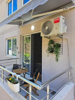a balcony with a fan and a table and chairs at Anja & Ogo apartments with Pool 2 in Petrovac na Moru