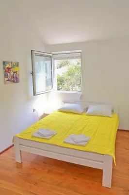 a bedroom with a yellow bed with two windows at Dream Bay View Loki in Kotor