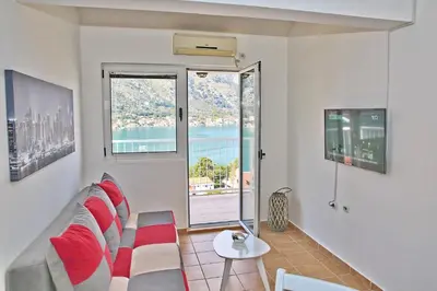 a living room with a couch and a large window at Dream Bay View Loki in Kotor