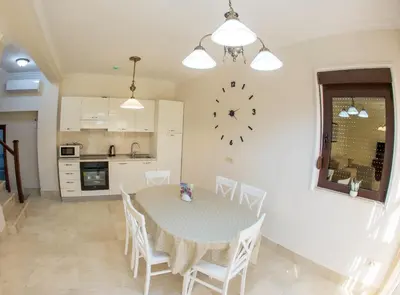 a dining room with a table and a clock on the wall at Townhouse Virginia in Petrovac na Moru