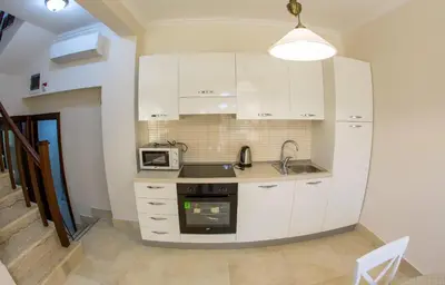 a kitchen with white cabinets and a sink and a microwave at Townhouse Virginia in Petrovac na Moru
