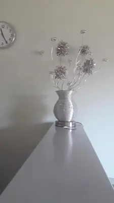 a vase with flowers in it next to a clock at Апартаменты Ирина М in Bar