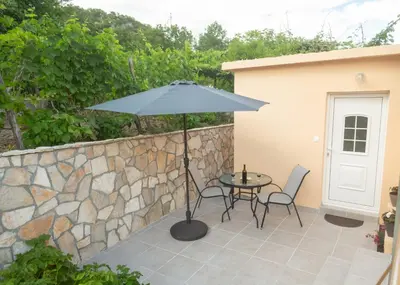 a patio with an umbrella and two chairs and a table at Apartment Milena in Virpazar