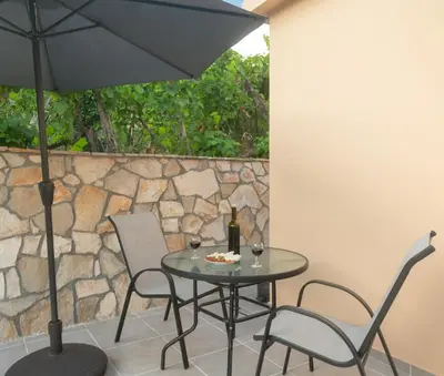 a table with two chairs and an umbrella on a patio at Apartment Milena in Virpazar