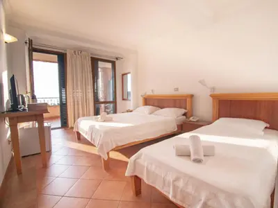a hotel room with two beds and a television at Apartments and Rooms Levantin Inn in Sveti Stefan