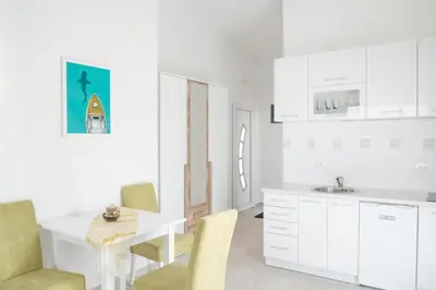 a kitchen with white cabinets and a table and chairs at Sunset Apartments in Ulcinj