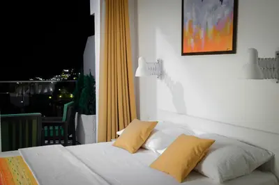 a white bed with two yellow pillows on a balcony at Sunset Apartments in Ulcinj