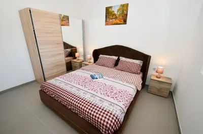 a bedroom with a bed with a red and white bedspread at Four Seasons Apartments in Kotor