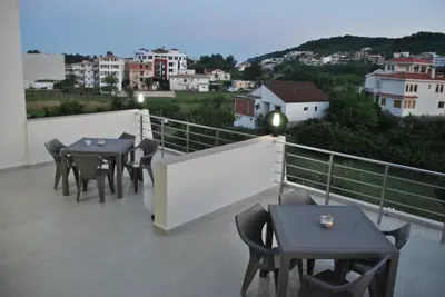 a balcony with tables and chairs and a view of a city at Haamel Apartment in Ulcinj