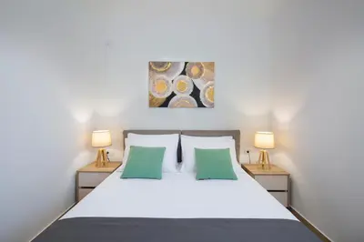a bedroom with a white bed with two lamps at Apartments Djuro Rafailovic in Budva