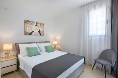 a bedroom with a bed and a chair and a window at Apartments Djuro Rafailovic in Budva