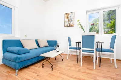 a living room with a blue couch and two chairs at Apartments Golden View in Kotor