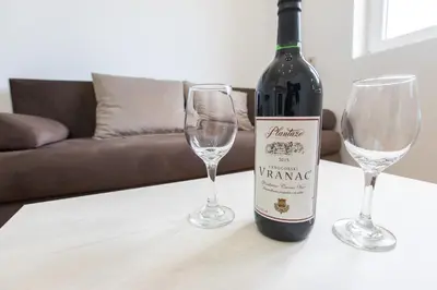 a bottle of wine and two wine glasses on a table at Apartments Golden View in Kotor