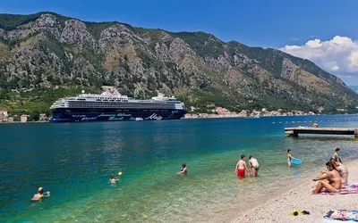 a group of people in the water at a beach with a cruise ship at Magnolia Old Town in Kotor