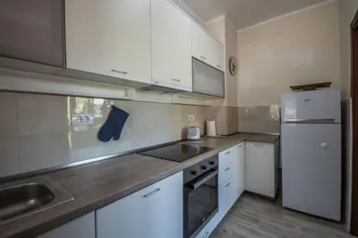 a kitchen with white cabinets and a sink and a refrigerator at Magnolia Old Town in Kotor