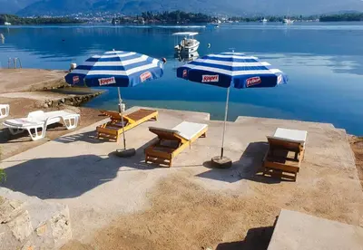 a group of chairs and umbrellas next to a lake at Luxury Apartment Maja in Tivat