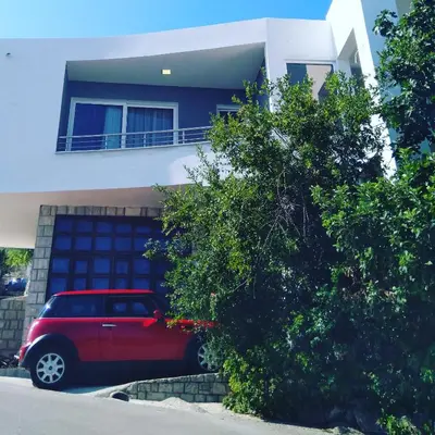 a red car parked in front of a house at Luka Apartment in Ulcinj
