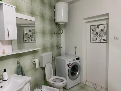 a bathroom with a toilet and a washing machine at Luka Apartment in Ulcinj