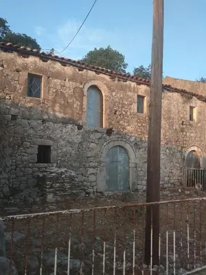an old stone building with a fence in front of it at Apartman 