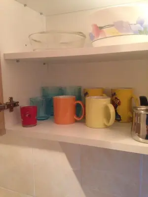 a row of coffee mugs sitting on a shelf at Apartment La Romana in Podgorica