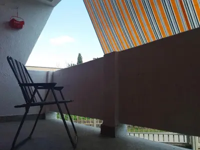 a chair sitting on a porch next to a wall at Apartment La Romana in Podgorica