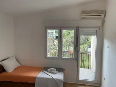 a bedroom with two windows and a bed and a balcony at Apartment Lazar & Marco in Podgorica