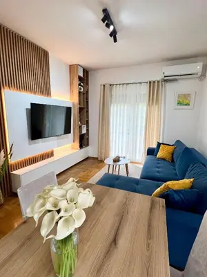 a living room with a blue couch and a vase with flowers at Bojovic's Apartment in Budva