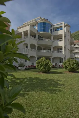 a large white building with a lawn in front of it at Vila V Lux Apartments in Petrovac na Moru