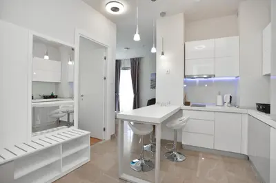 a white kitchen with white cabinets and a counter at Apartments Menuet in Budva