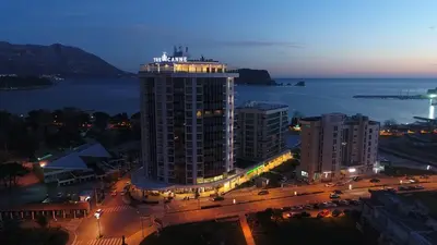 a tall building with lights on top of it at night at Apartments Menuet in Budva
