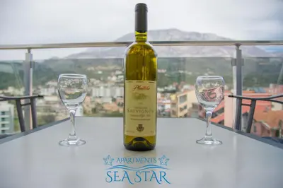 a bottle of wine and two wine glasses on a table at Sea Star Apartment in Dobra Voda
