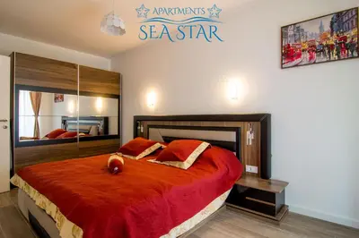 a bedroom with a bed with a red comforter at Sea Star Apartment in Dobra Voda
