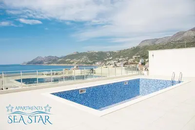 a swimming pool on the roof of a building with the ocean at Sea Star Apartment in Dobra Voda