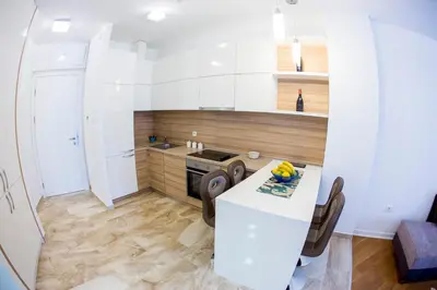 a kitchen with white cabinets and a table with chairs at Apartman Anna Tre Canne Budva in Budva