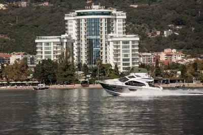 a boat in the water in front of a city at Apartman Anna Tre Canne Budva in Budva