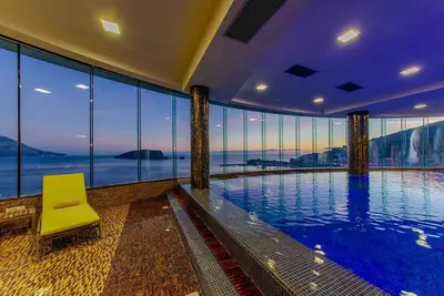 a swimming pool in a building with a yellow chair at Apartman Anna Tre Canne Budva in Budva