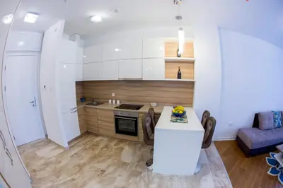 a kitchen with white cabinets and a table with chairs at Apartman Anna Tre Canne Budva in Budva