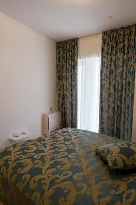 a bedroom with a bed and a window with curtains at Apartman Anna Tre Canne Budva in Budva
