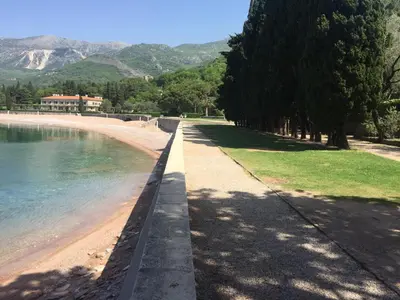 a sidewalk next to a beach with trees and water at Apartment Galina Przno in Budva