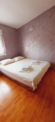 a bedroom with a large bed with a wooden floor at Apartmani Palma in Sutomore