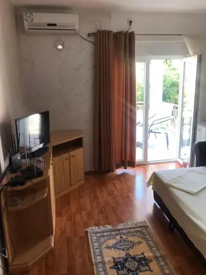 a bedroom with a bed and a desk with a television at Apartmani Palma in Sutomore