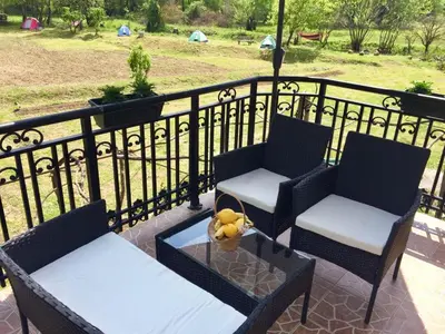 a balcony with two chairs and a table with a bowl of fruit at Camp Podkraj in Virpazar